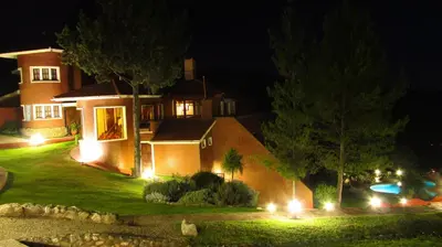 a house with lights in the yard at night at Chalet Suisse Posada & SPA - Adults only in Villa General Belgrano