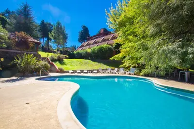 a swimming pool with chairs and a house in the background at Chalet Suisse Posada & SPA - Adults only in Villa General Belgrano