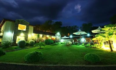a resort with a yard with tables and umbrellas at night at Apart Hotel Las Palmeras in Villa General Belgrano