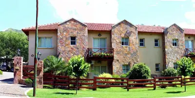 a house with a fence in front of it at Apart Hotel Las Palmeras in Villa General Belgrano