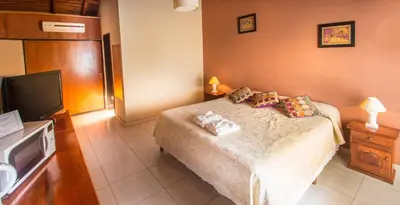 a bedroom with a bed and a flat screen tv at Apart Hotel Las Palmeras in Villa General Belgrano