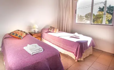 a room with two beds with purple sheets and a window at Apart Hotel Las Palmeras in Villa General Belgrano