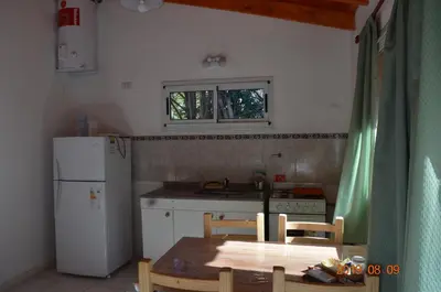 a small kitchen with a table and a white refrigerator at Alquimia Cabañas in San Francisco del Monte de Oro