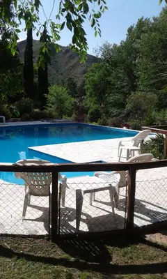 a table and chairs next to a swimming pool at Posada Shemak in Villa General Belgrano