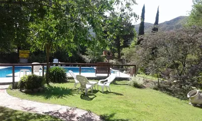 two white chairs sitting in the grass near a pool at Posada Shemak in Villa General Belgrano