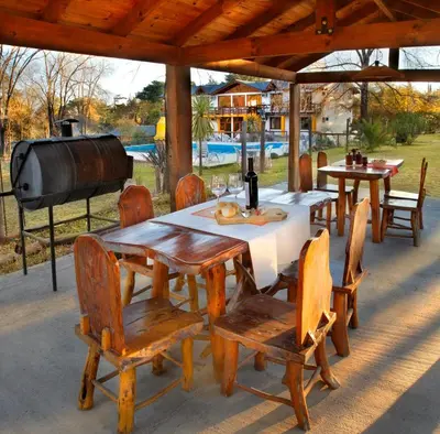 a wooden table and chairs with a grill and a table and chairs at Posada Shemak in Villa General Belgrano