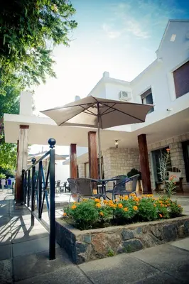 a patio with an umbrella and chairs and flowers at Casablanca Hotel & Spa in Santa Rosa de Calamuchita