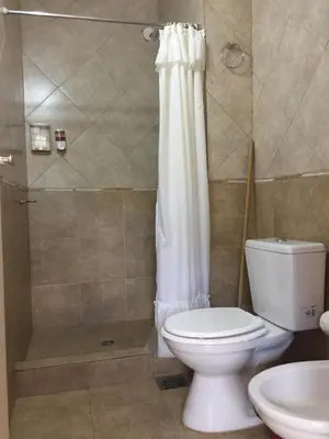 a bathroom with a white toilet and a shower at Hotel Gloria in Santa Rosa de Calamuchita