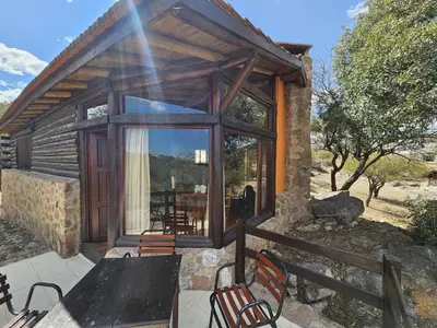 a cabin with a table and chairs on a patio at Los Ancares Resort in Mina Clavero