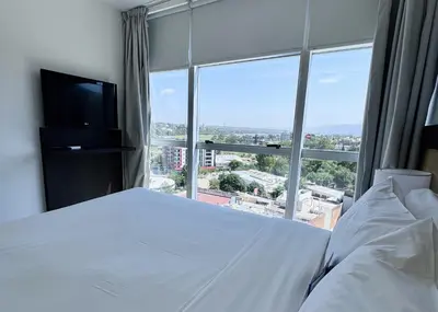 a bedroom with a white bed and a large window at Amérian Carlos Paz in Villa Carlos Paz