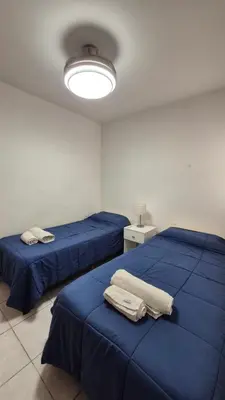 two beds in a room with blue sheets and a light at M772- Departamento temporal in Cordoba