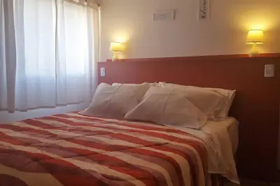 a bed in a bedroom with two lamps on the wall at Alegre, luminoso y tranquilo en la mejor ubicación in Cordoba