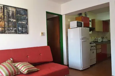 a red couch in a kitchen with a white refrigerator at Alegre, luminoso y tranquilo en la mejor ubicación in Cordoba