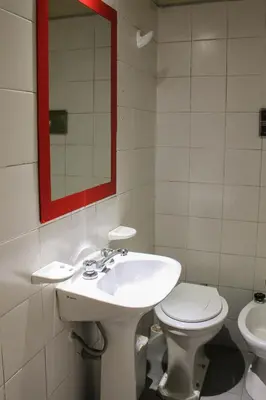 a bathroom with a sink and a toilet and a mirror at Casi Guemes Hotel in Cordoba