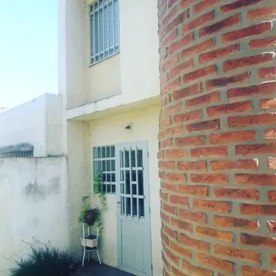 a brick building with a white door and a chair at DUPLEX - COCHERA CUBIERTA in Cordoba