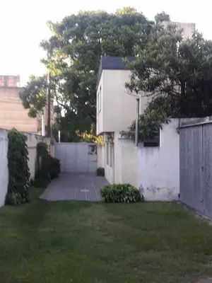 a yard with a white house and a fence at DUPLEX - COCHERA CUBIERTA in Cordoba