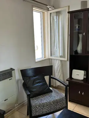 a black chair sitting in a room with a window at Departamento en Barrio Guemes in Cordoba