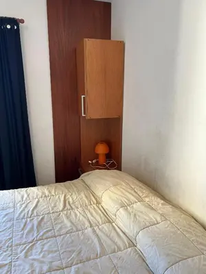 a bedroom with a bed with a cabinet and a lamp at Departamento en Barrio Guemes in Cordoba