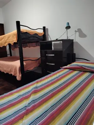 a bed with a dresser and a colorful striped blanket at HA! 2 Resi para estudiantes in Cordoba