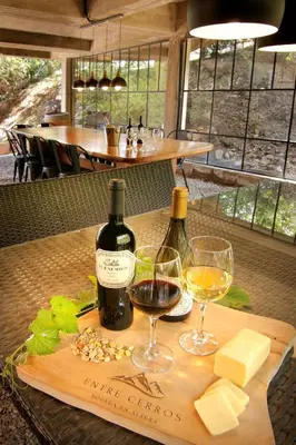 a wooden table with two glasses of wine and cheese at Terrazas de Belgrano - Club de Montaña in Villa General Belgrano