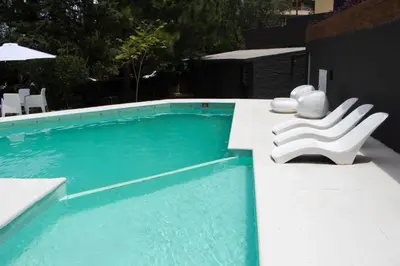 a swimming pool with two white chairs sitting next to it at Hotel Terrazas by CPH in Villa Carlos Paz