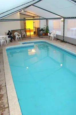 a large swimming pool with blue water in a building at Hotel Temu in Villa Carlos Paz