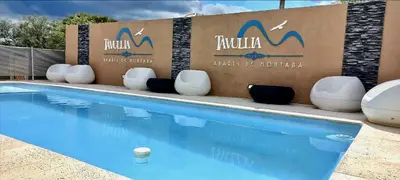 a swimming pool with chairs next to a hotel sign at Aparts de Montaña Tavullia in Carpintería