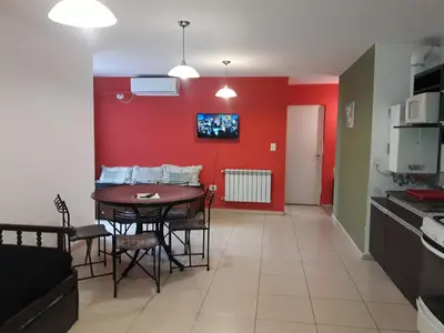 a living room with a table and a red wall at Abuela Chela in Villa Carlos Paz