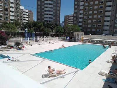 a large swimming pool with people sitting in chairs in it at Villasol Temporario in Cordoba