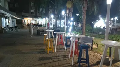 a group of tables and stools on a sidewalk at night at Villasol Temporario in Cordoba