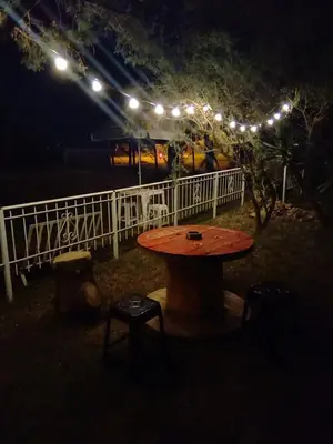 a table and chairs in front of a fence with lights at Complejo Los Sauces in Mina Clavero