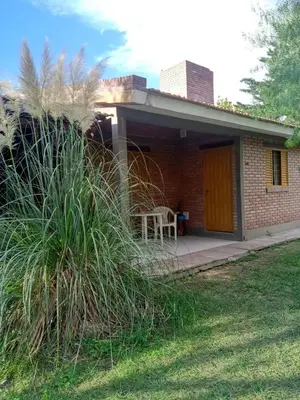 a brick house with a table and a chair on a porch at Complejo Los Sauces in Mina Clavero