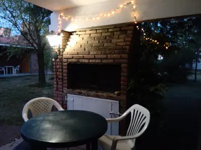 a patio with a table and chairs and a brick fireplace at Complejo Los Sauces in Mina Clavero
