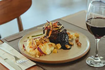 a plate of food on a table with a glass of wine at La Urumpta Hotel, AKEN MIND in Río Cuarto