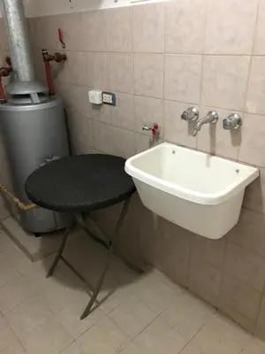 a bathroom with a sink and a chair next to it at Saint Michel Departamentos para turismo in Alta Gracia