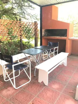 a table and chairs and a bench on a patio at Alondra Apart in Villa Cura Brochero