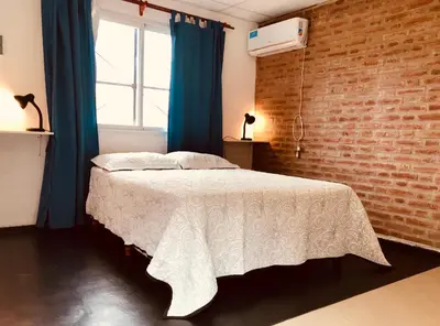 a bedroom with a white bed with a brick wall at Alondra Apart in Villa Cura Brochero