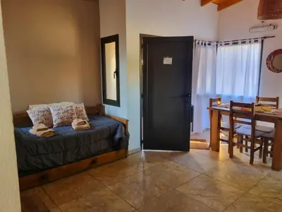 a bedroom with a bed and a table and a door at CABAÑAS SUKHA in Santa Rosa de Calamuchita