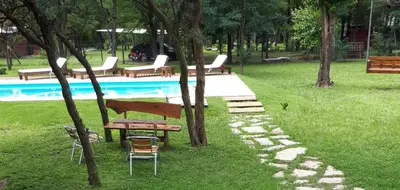 a park with a picnic table and chairs next to a pool at CABAÑAS SUKHA in Santa Rosa de Calamuchita