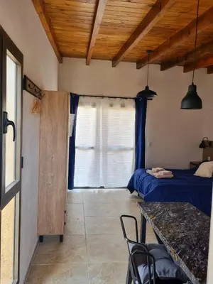 a bedroom with a bed and a table and a window at CABAÑAS SUKHA in Santa Rosa de Calamuchita