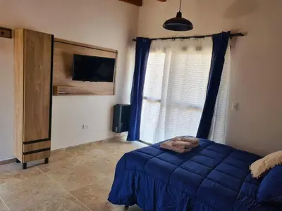 a bedroom with a blue bed and a window at CABAÑAS SUKHA in Santa Rosa de Calamuchita