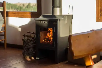 a wood stove with a fire in a room at Los Abedules Cabañas in Villa Alpina