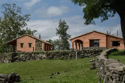 a house and a stone wall next to a building at Los Abedules Cabañas in Villa Alpina
