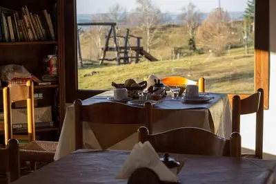 a table with a view of a field through a window at Los Abedules Cabañas in Villa Alpina