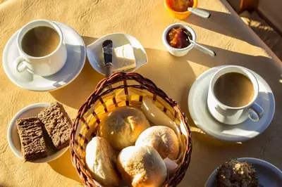 a table with cups of coffee and a basket of bread at Los Abedules Cabañas in Villa Alpina