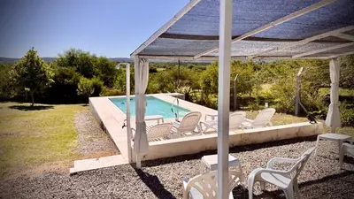 a swimming pool with white chairs and a gazebo at ARROYO SUITE HOUSE in Mina Clavero