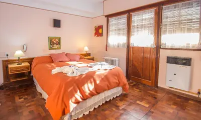 a bedroom with a bed with orange sheets and a window at Las Verbenas Hotel in La Cumbrecita