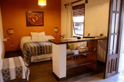 a bedroom with a bed and a desk with a sink at La Catalina Suites de Campo in Nono