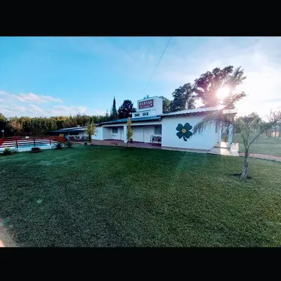 a white building with a large yard in front of it at Hostal El Trébol - Tanti in Tanti