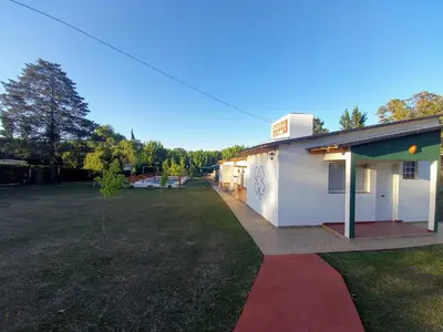a white building with a large yard in front of it at Hostal El Trébol - Tanti in Tanti